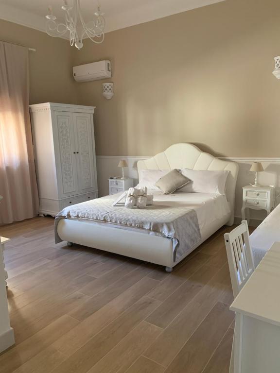 um quarto com uma cama branca e pisos em madeira em Palma Salentina em Lizzano