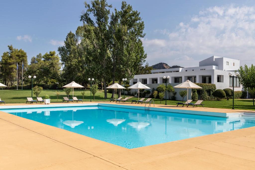 a pool with chairs and umbrellas in front of a building at Amalia Hotel Olympia in Olympia