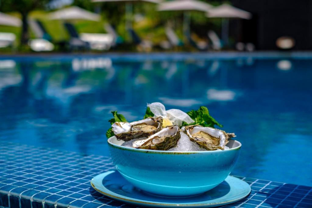 a bowl of oysters next to a swimming pool at Herdade da Cortesia Hotel in Avis
