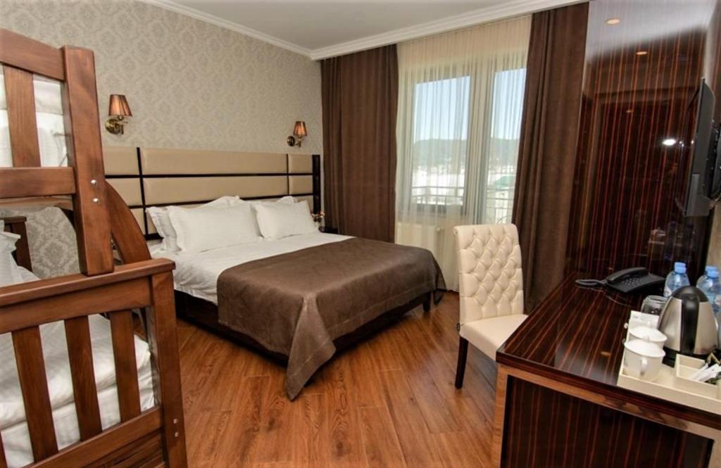 um quarto de hotel com uma cama e uma secretária e um quarto em Hotel King David Bakuriani em Bakuriani
