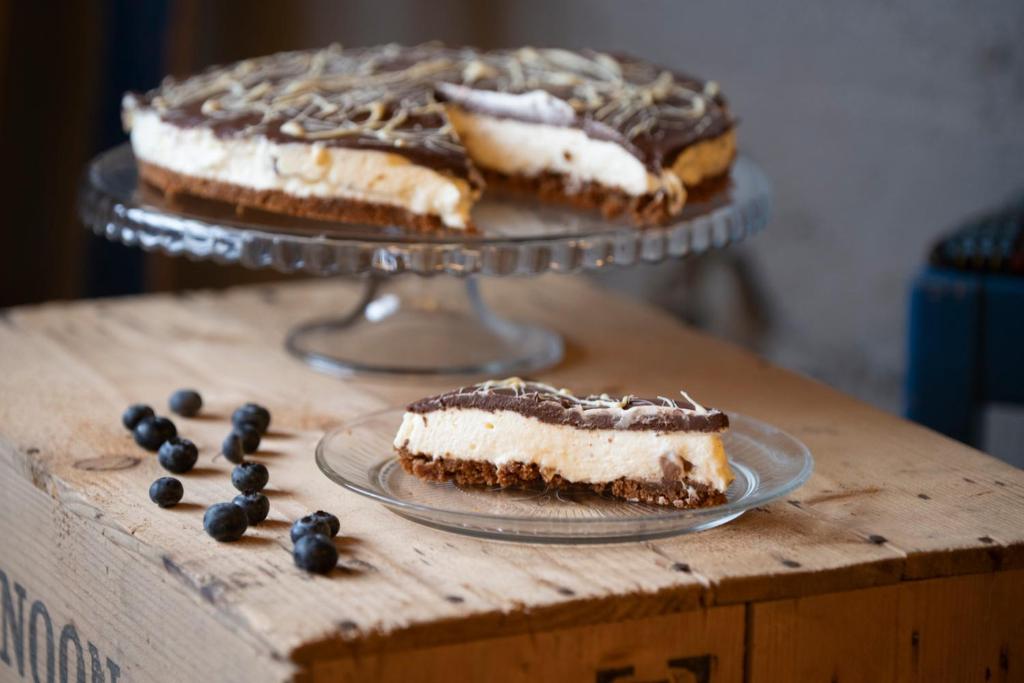 a piece of cake on a wooden table with two desserts at Sjávarborg in Stykkishólmur