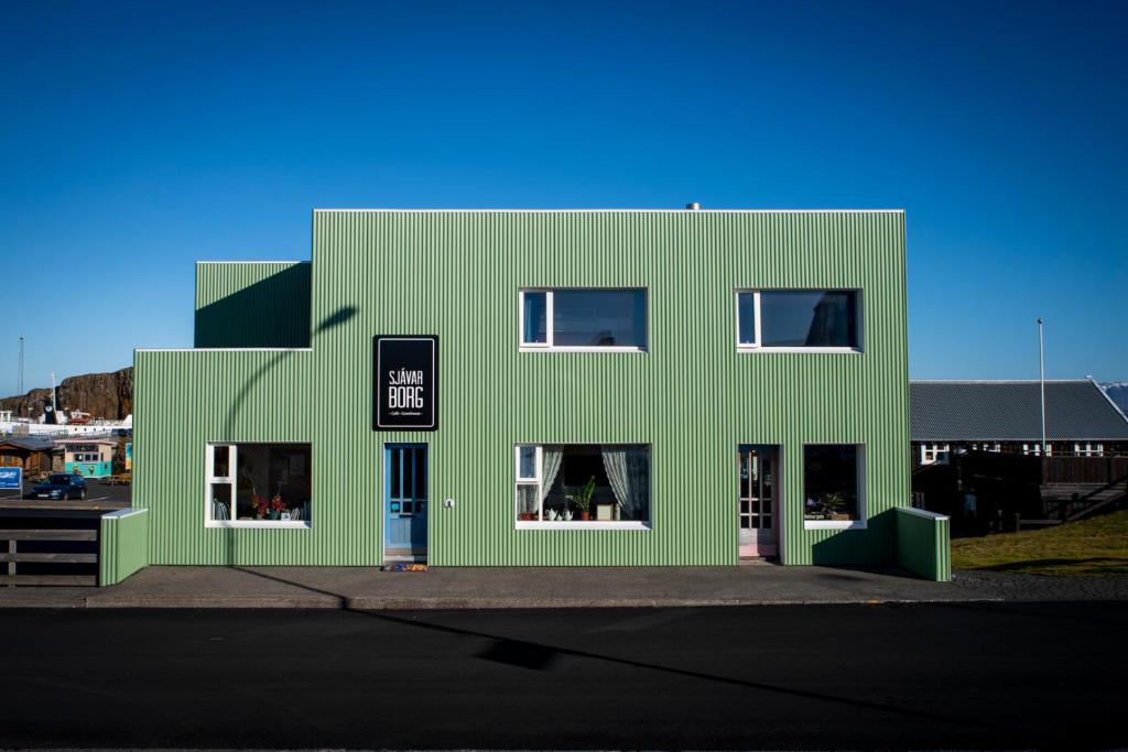 un bâtiment vert avec des fenêtres blanches sur une rue dans l'établissement Sjávarborg, à Stykkishólmur