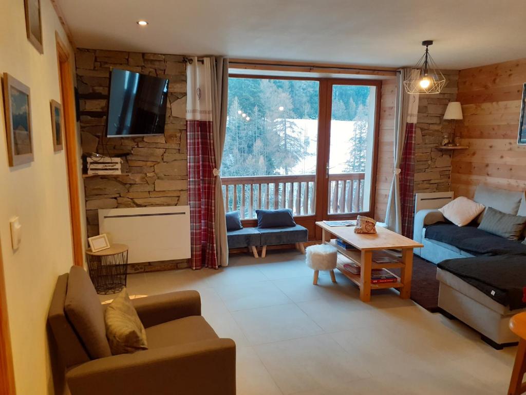 uma sala de estar com um sofá, uma mesa e uma televisão em Appartement chaleureux avec wifi de 10 personnes à Val-Cenis em Lanslebourg-Mont-Cenis