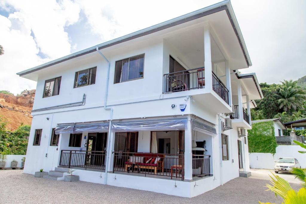 una casa blanca con sillas rojas delante en Riverside Mount Simpson - Seychelles Island en Mahe