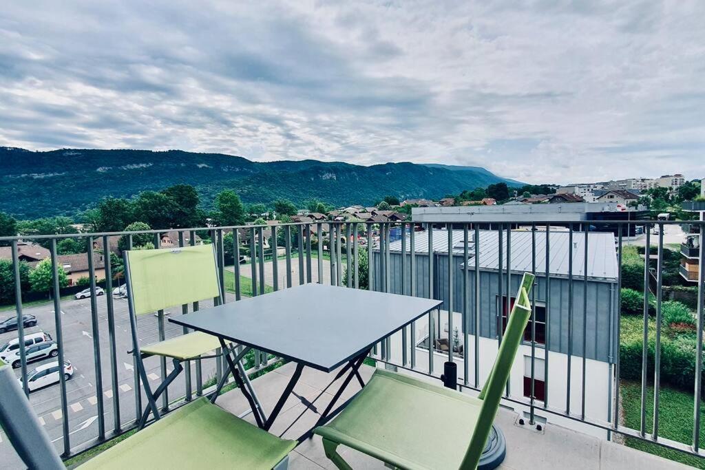 une table et des chaises sur un balcon avec vue dans l'établissement Les Hauteurs d'Annecy 2 étoiles entre lac et montagne, à Annecy
