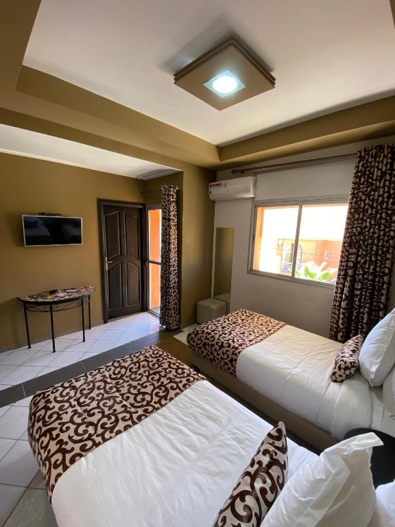 two beds sitting in a room with a window at Hotel VELSATIS in Beni Mellal