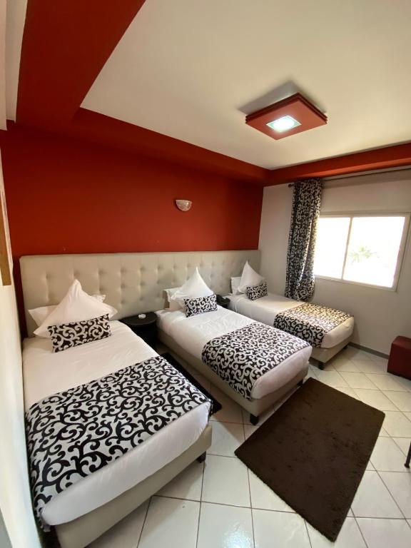 two beds in a room with red walls at Hotel VELSATIS in Beni Mellal