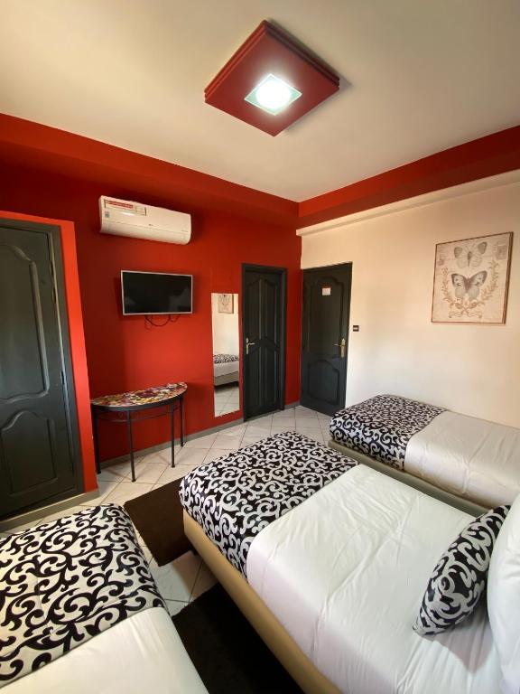 two beds in a room with red walls at Hotel VELSATIS in Beni Mellal