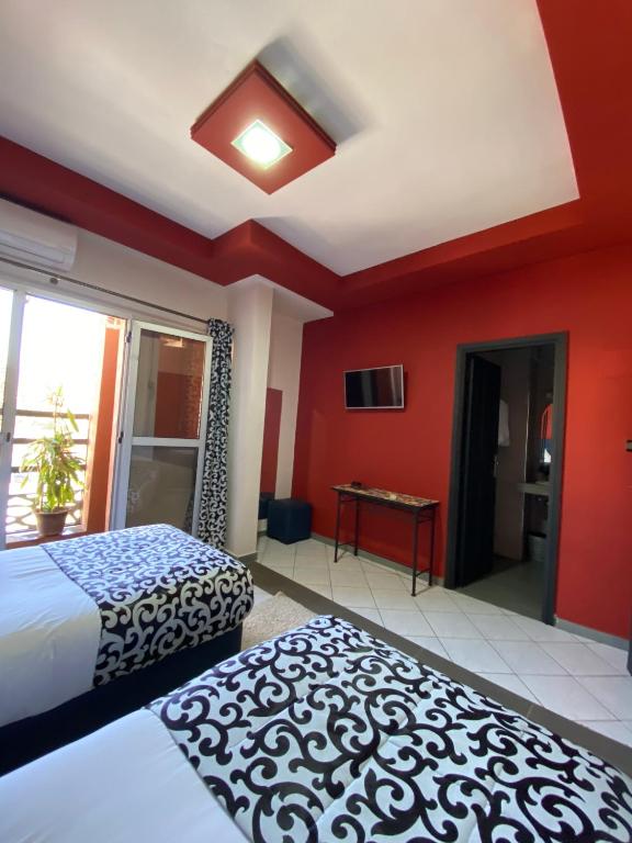a bedroom with two beds and a red wall at Hotel VELSATIS in Beni Mellal