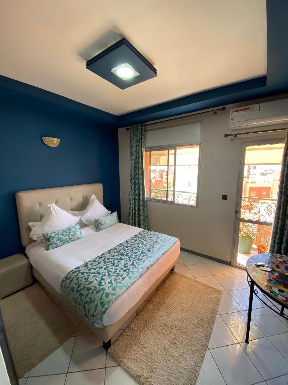 a bedroom with a bed with blue walls and a window at Hotel VELSATIS in Beni Mellal
