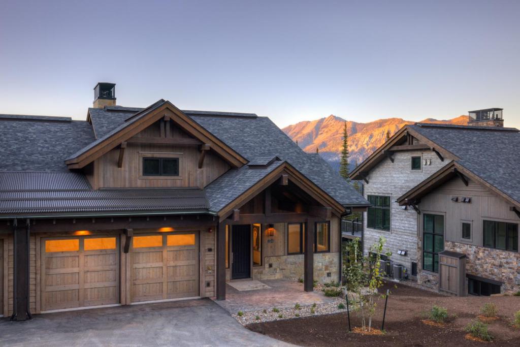 a house with a garage with mountains in the background at Inspiration Point Townhome 1B in Big Sky