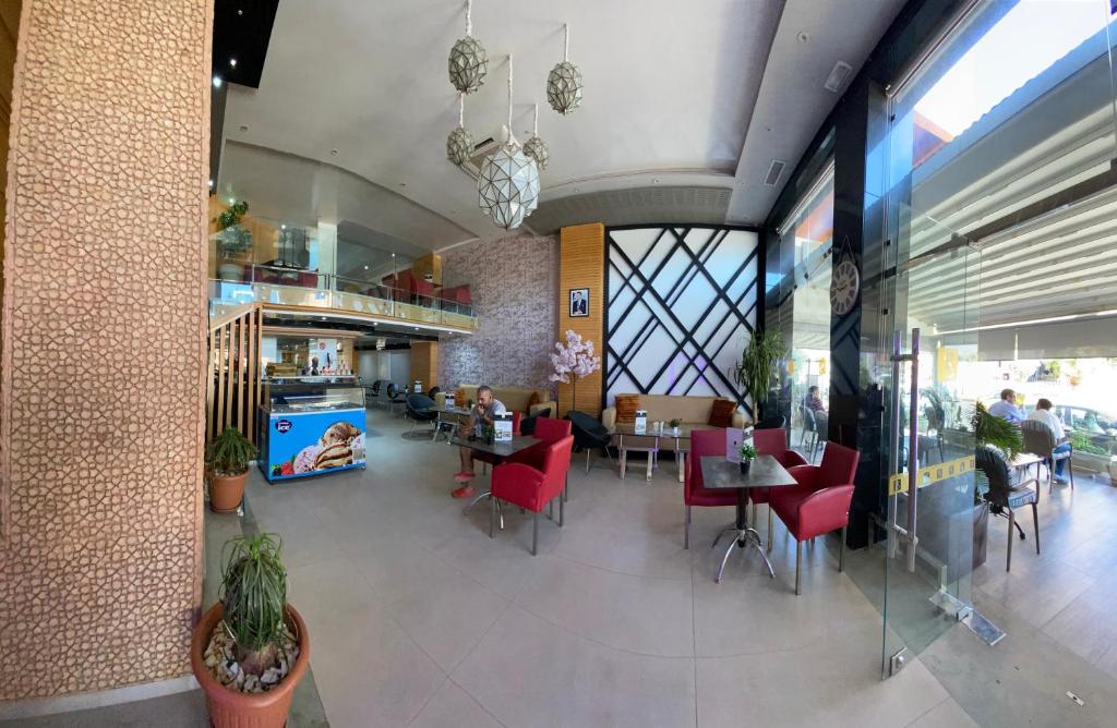 a restaurant with red chairs and tables in a building at Hotel VELSATIS in Beni Mellal