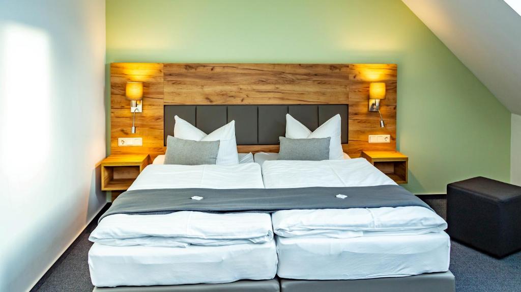 1 dormitorio con 1 cama grande con sábanas y almohadas blancas en City-Hotel-Wolgast en Wolgast
