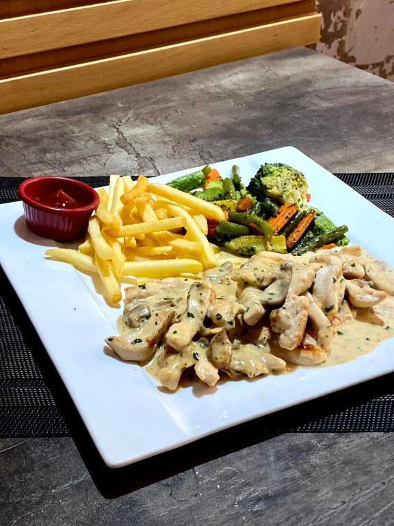 a plate of food with french fries and chicken and vegetables at Hotel VELSATIS in Beni Mellal