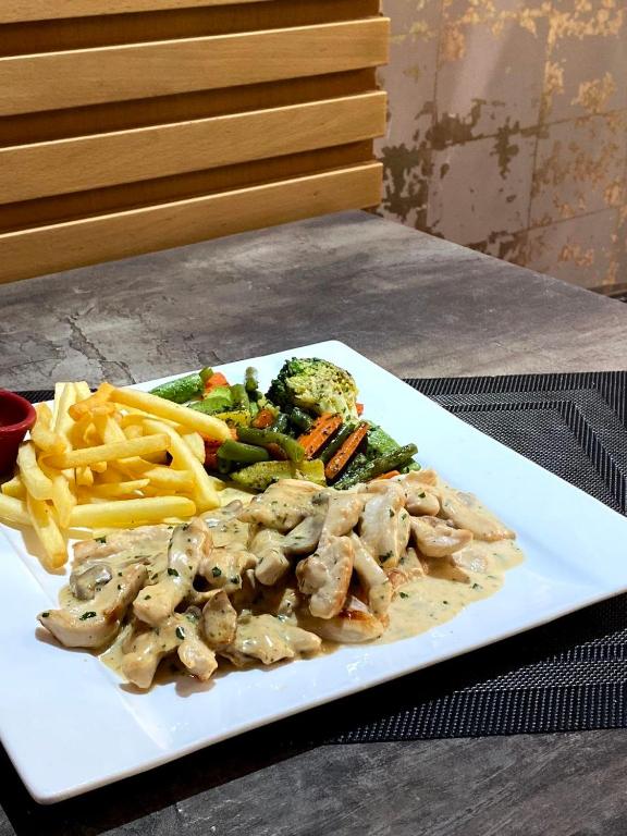 a white plate of food with french fries and broccoli at Hotel VELSATIS in Beni Mellal