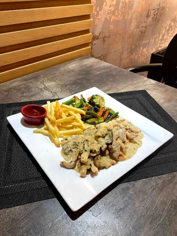 a plate of food with fries and vegetables on a table at Hotel VELSATIS in Beni Mellal