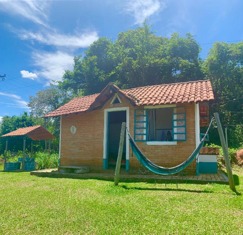 uma pequena casa com uma rede em frente em Pousada Shangrilá São Thomé em São Thomé das Letras