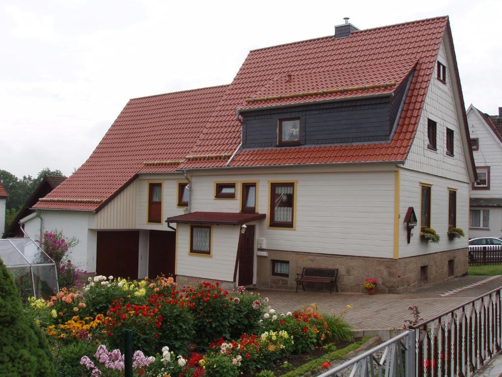 a white house with a red roof and some flowers at Ferienwohnungen Rießling in Elend