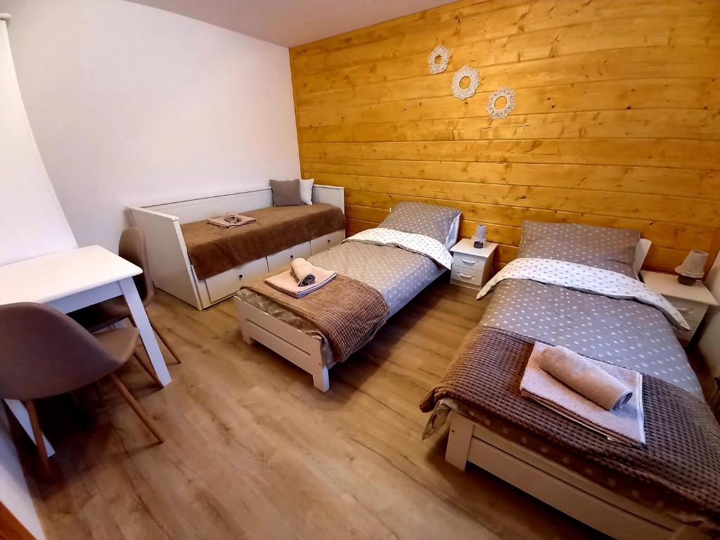 a room with three beds and a wooden wall at Noclegi Majowy Zakątek in Zboiska