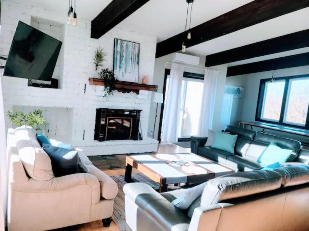 a living room with leather furniture and a fireplace at Northview Swiss Style Chalet in Blue Mountains