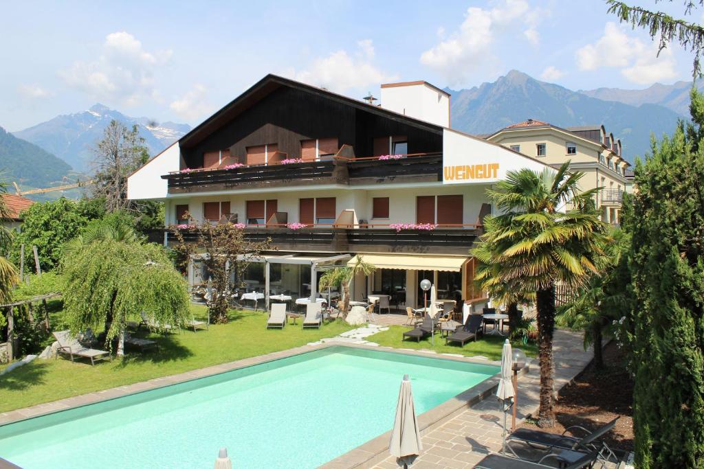a hotel with a swimming pool in front of a building at Garni Weingut in Merano