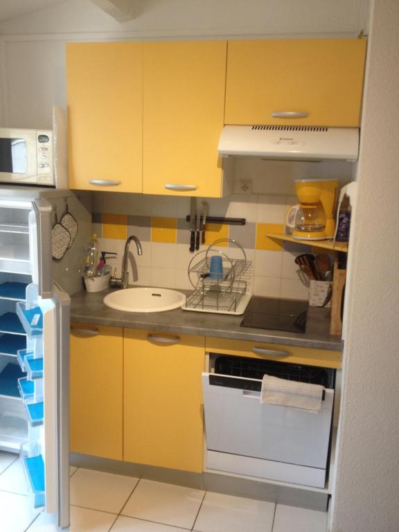 a kitchen with yellow cabinets and a sink at CAP D&#39;AGDE studio cabine 6 pers. + terrasse + parking privé + clim (calme) in Cap d&#39;Agde