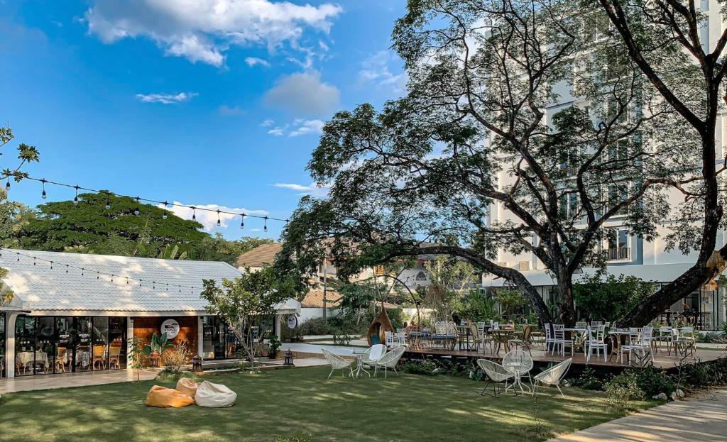 a garden with chairs and tables in front of a building at Tree Tara hotel in Lampang