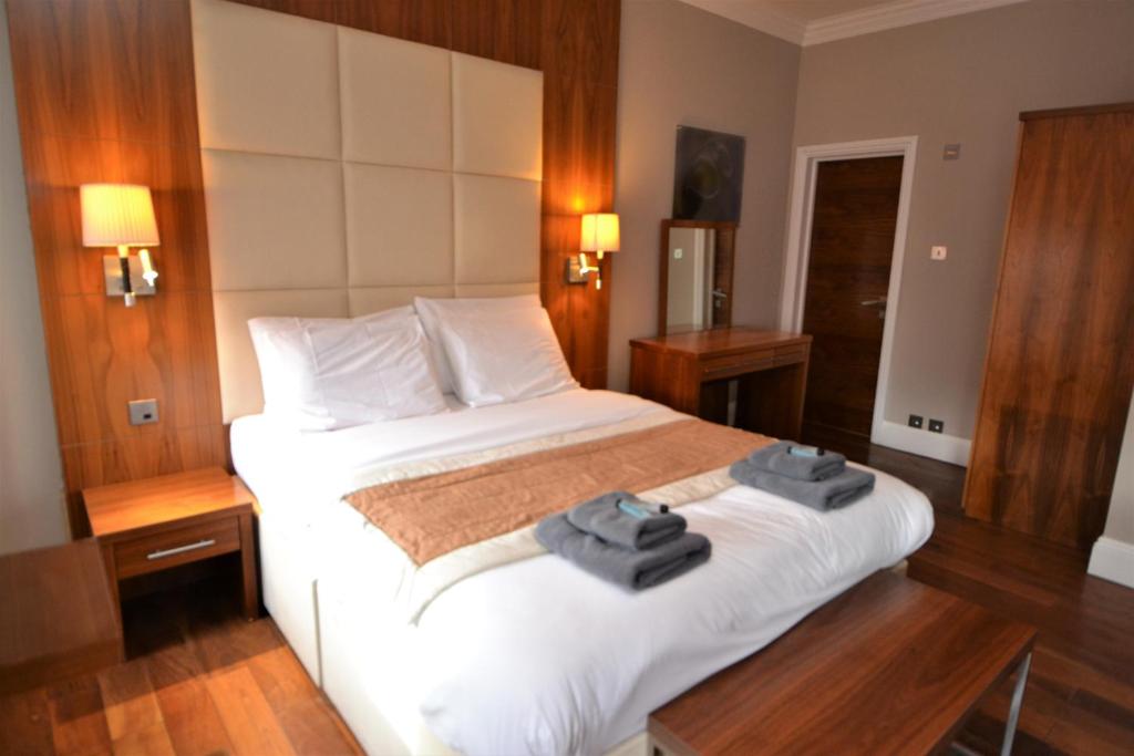 Una habitación de hotel con una cama con toallas. en Sloane Square Apartments en Londres