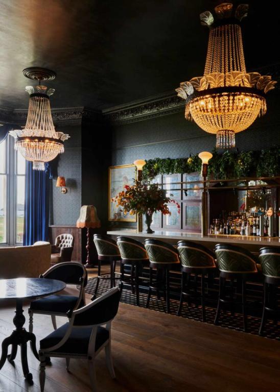 a bar with chairs and tables and chandeliers at Marine North Berwick in North Berwick