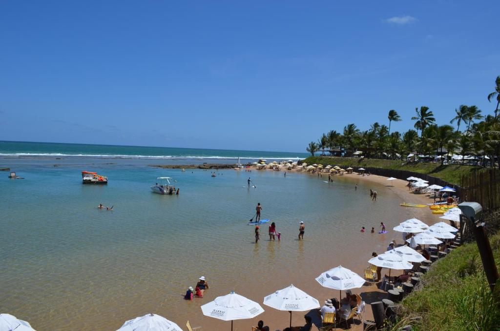 a beach with umbrellas and people in the water at Condomínio Nannai Residence - Anchova 01 in Porto De Galinhas