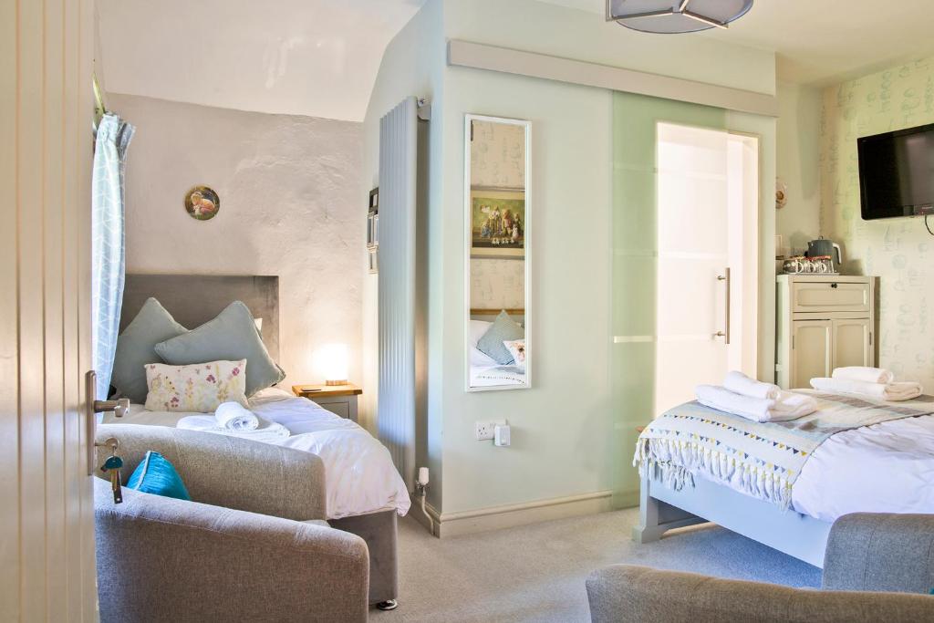 a bedroom with two beds and a chair at Hawthorn Farm Guest House in Buxton