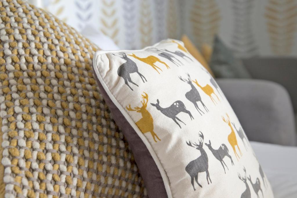 a pillow with deer on it sitting on a couch at Hawthorn Farm Guest House in Buxton