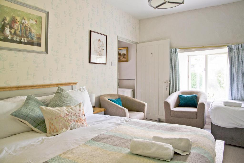a bedroom with a bed and two chairs and a window at Hawthorn Farm Guest House in Buxton
