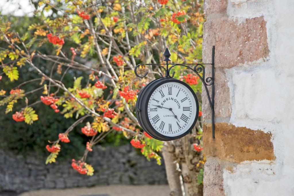a clock on the side of a wall with flowers at Hawthorn Farm Guest House in Buxton