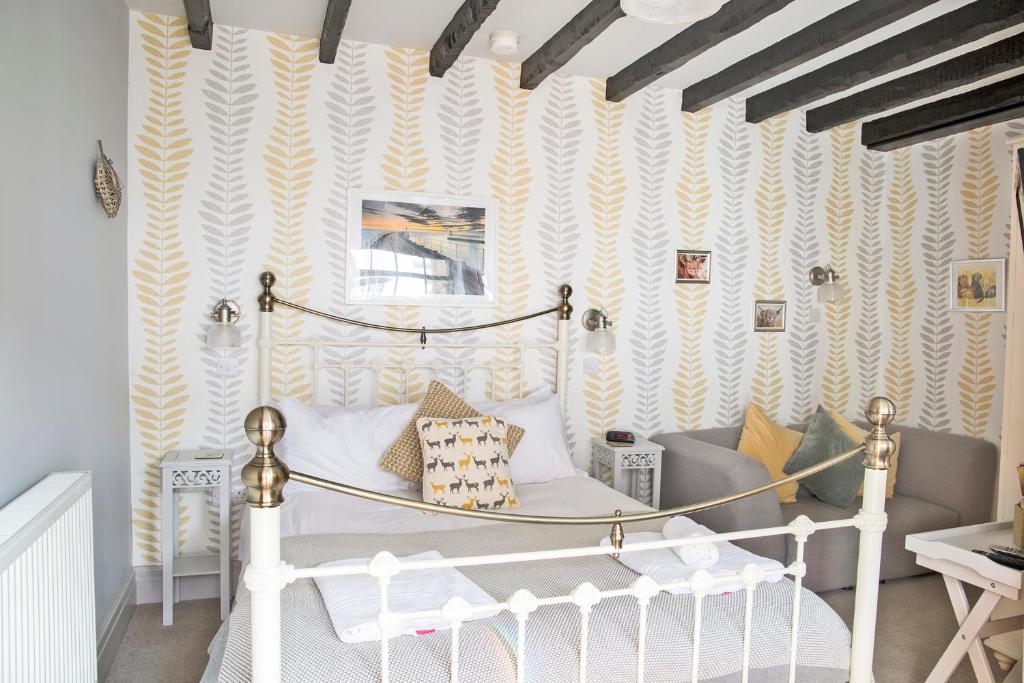 a bedroom with a white bed and yellow and white wallpaper at Hawthorn Farm Guest House in Buxton