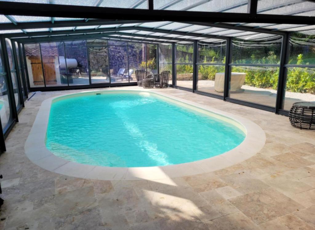 a swimming pool in a house with a glass extension at Villa confortable à Carlux avec piscine privée et jardin in Carlux