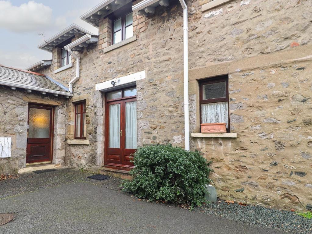 een stenen huis met een rode deur en ramen bij Coach House Cottage in Carnforth