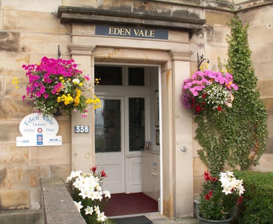 a entrance to a building with flowers in front of it at Eden Vale Garden View Apartment with Patio in Morecambe