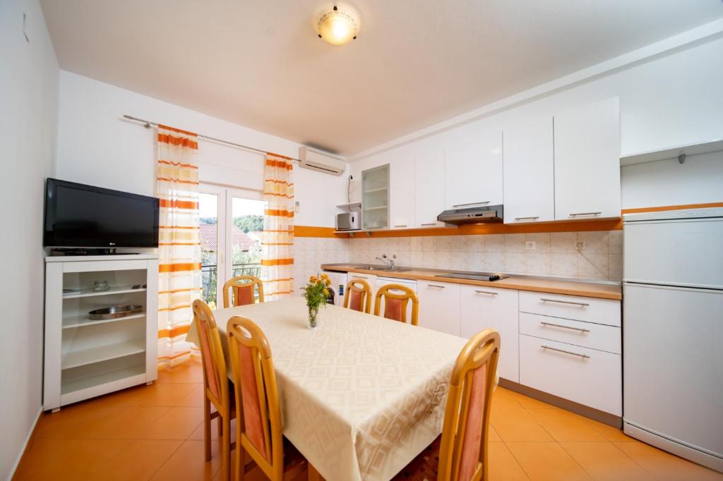 a kitchen with a table and chairs and a television at Apartments Rajska Plaza (129) in Lopar