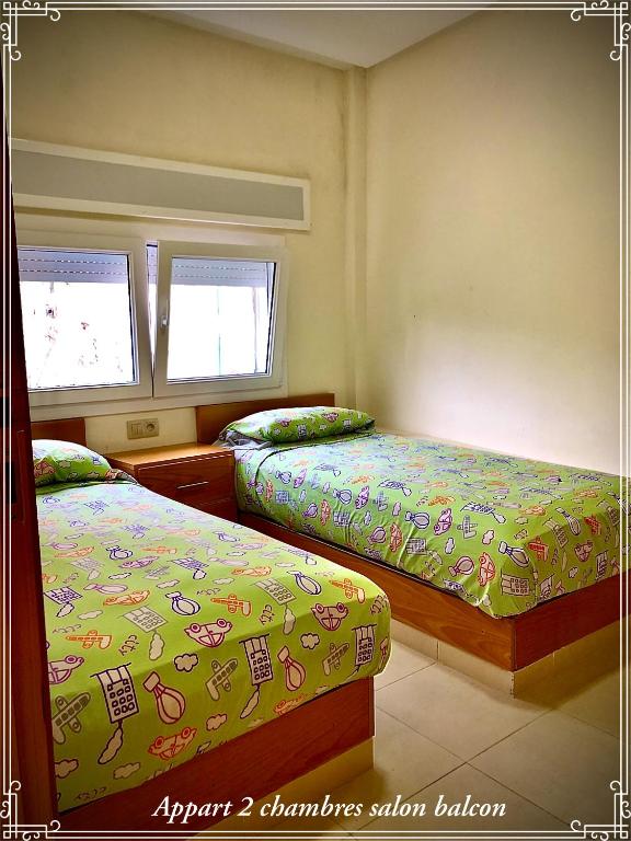 een slaapkamer met 2 bedden en 2 ramen bij Hôtel Réstinga Martil in Martil