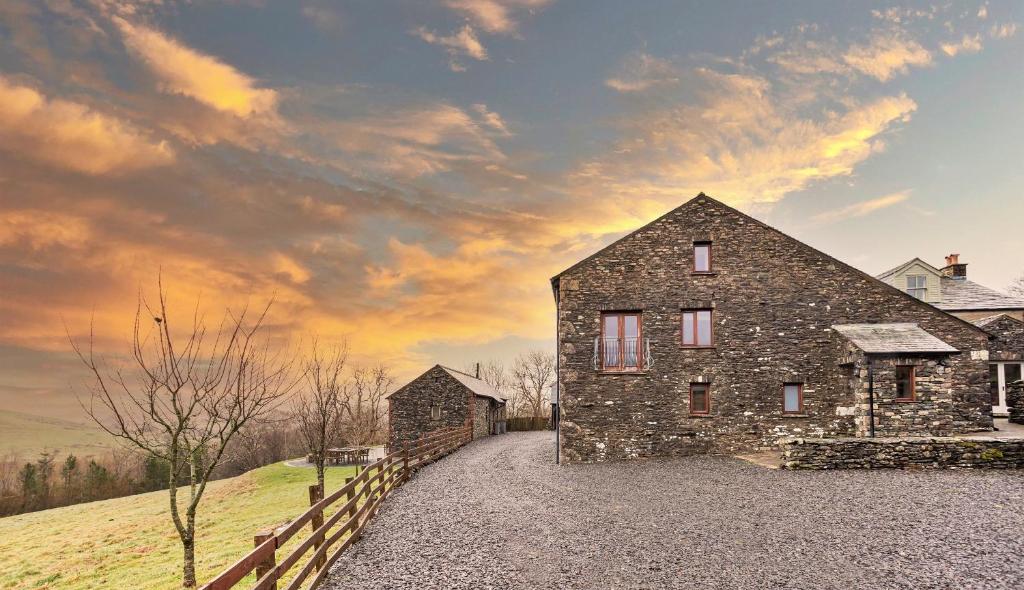 una casa de piedra en una colina con una valla en Finest Retreats - Bretherdale Barn en Tebay