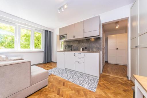 uma cozinha com armários brancos e um sofá num quarto em Apartament wakacyjny na Przymorzu em Gdansk
