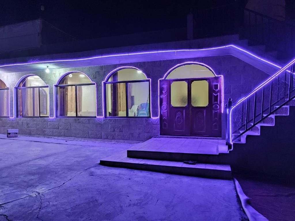 private room with cultural experience and great landscapes في Şirfah: منزل به أضواء أرجوانية على الباب الأمامي