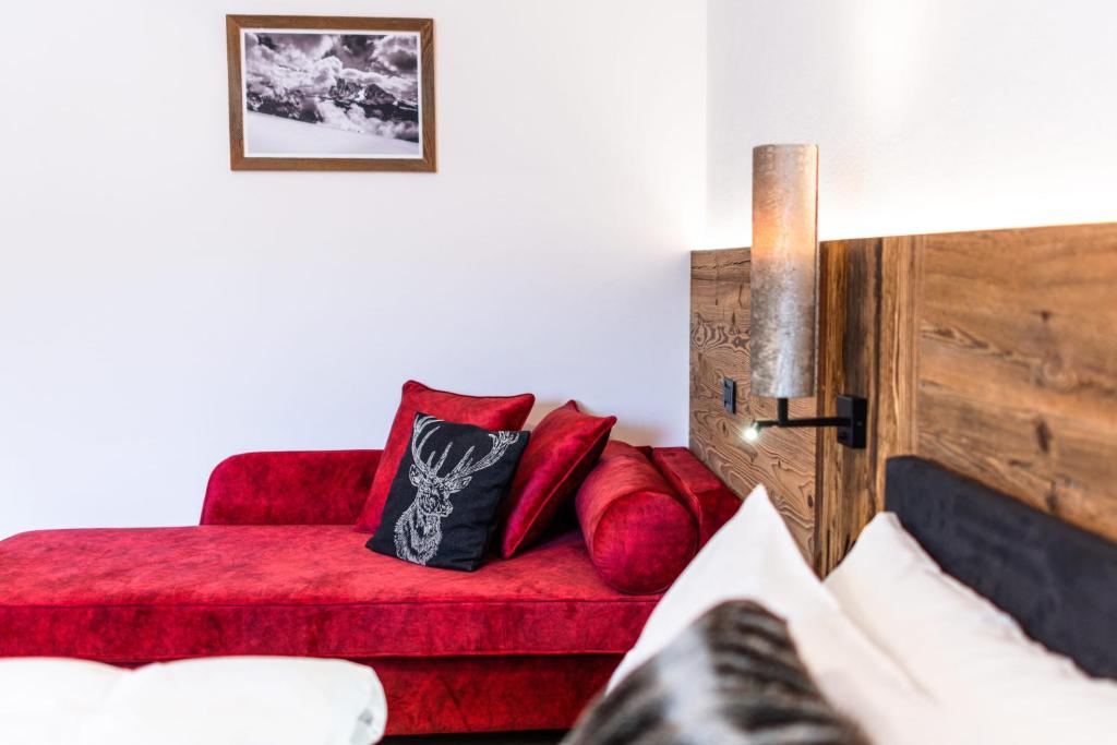 a living room with a red couch and a red chair at Apartments Rainer - Val Gardena in Ortisei