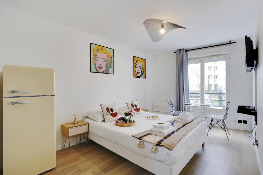 Dieses weiße Zimmer verfügt über ein Bett und einen Kühlschrank. in der Unterkunft Buttes Chaumont - Sunny 2P apartment in Paris