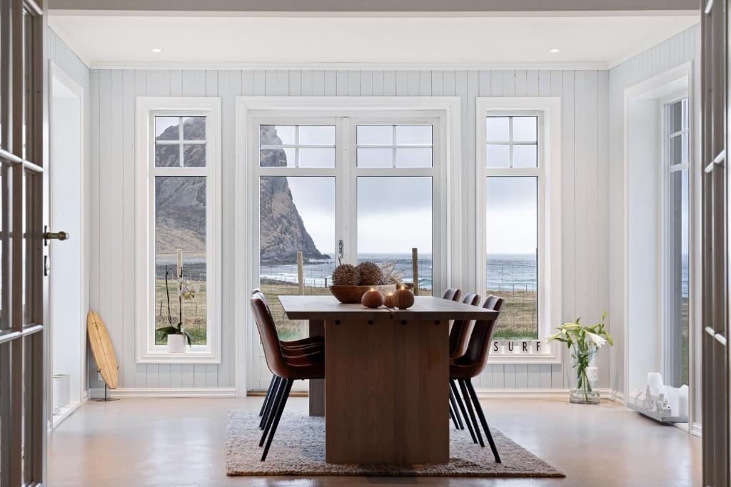 a dining room with a table and chairs and windows at Unstad Arctic Resort in Unstad