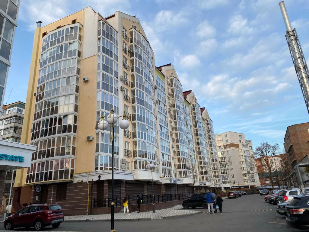 un gran edificio en una calle de la ciudad con coches aparcados en Світлі апартаменти в самому Центрі біля Корпусного парку - Мережа HELEN, en Poltava