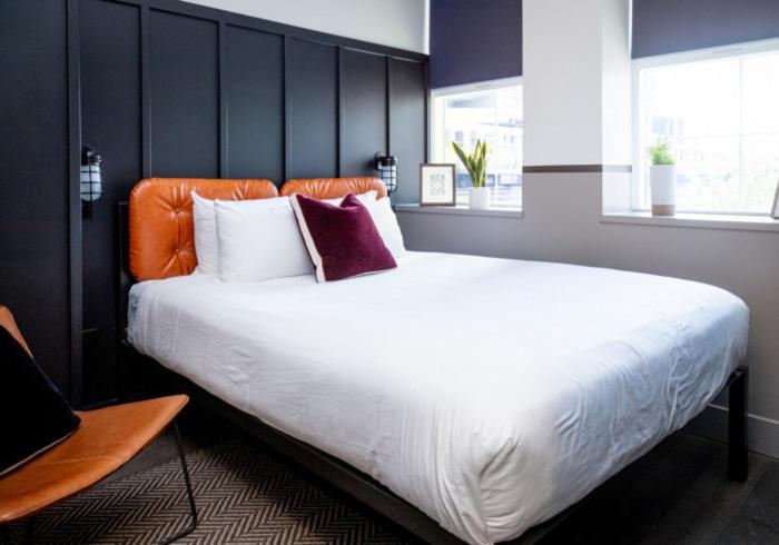 - une chambre avec un grand lit blanc et une tête de lit orange dans l'établissement The Chicago Hotel Collection River North, à Chicago
