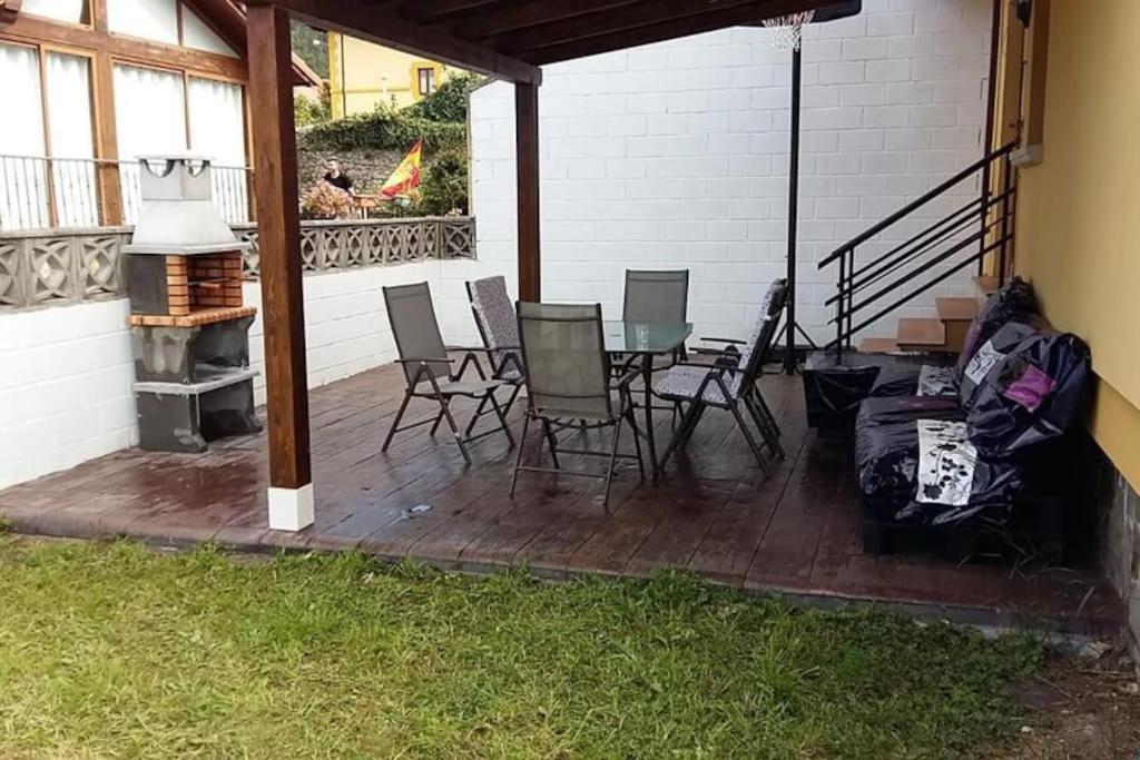 un patio con sillas, una mesa y una parrilla en Villa Miguel, en Arnuero