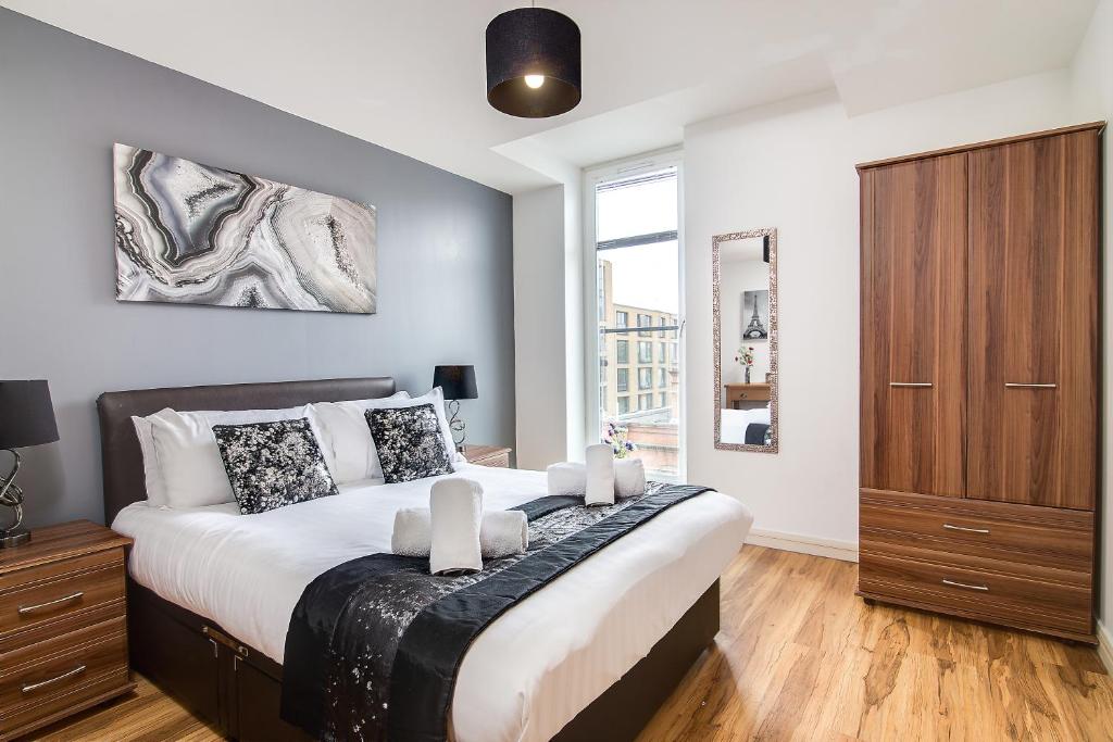 een slaapkamer met een groot bed en een houten kast bij Chinatown Birmingham Apartments in Birmingham